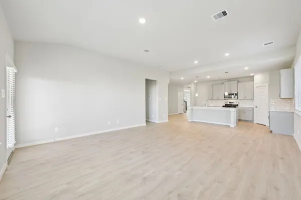 a view of kitchen with kitchen island a sink wooden floor and white cabinets