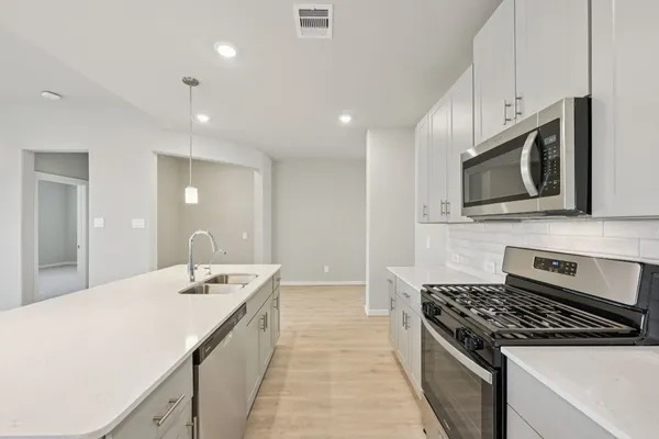 a large kitchen with stainless steel appliances granite countertop a sink a stove oven and white cabinets