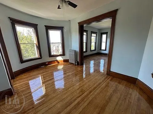 an empty room with wooden floor and windows