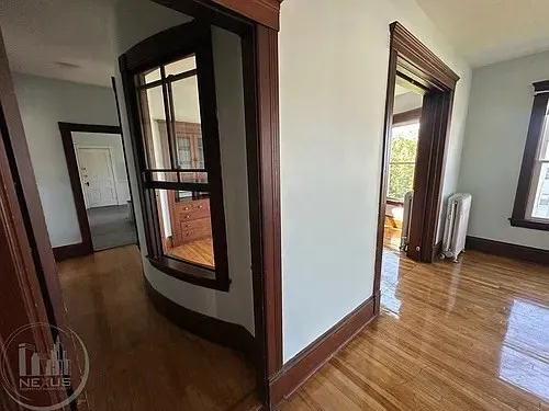 a view of a hallway with wooden floor and windows