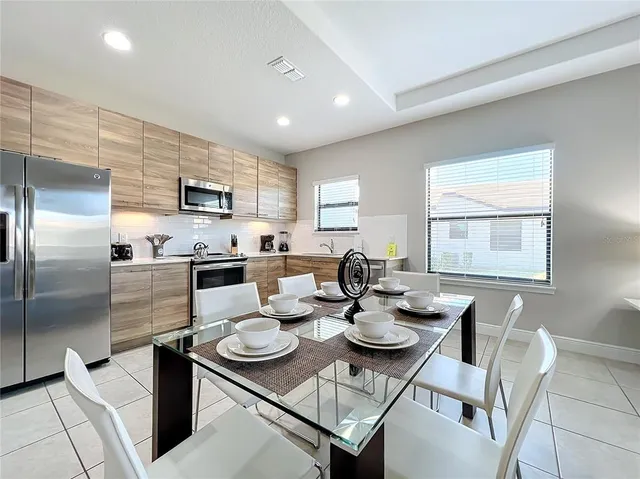 a kitchen with a refrigerator a stove a dining table and chairs