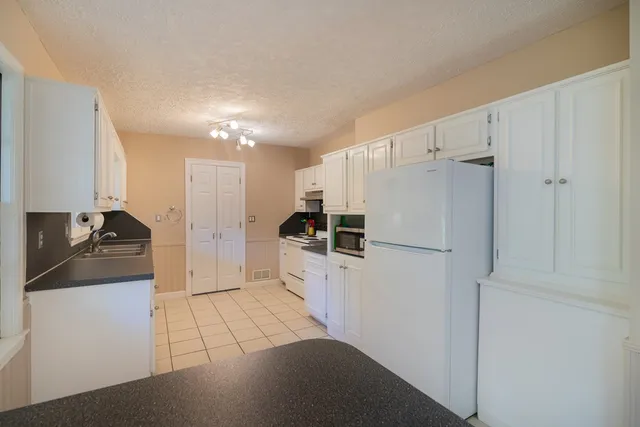 a kitchen with granite countertop a refrigerator and a sink