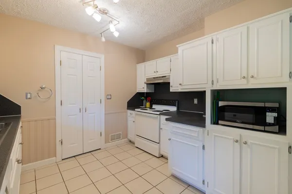 a kitchen with white cabinets and appliances