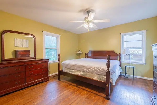 a bedroom with a bed and a dresser with wooden floor