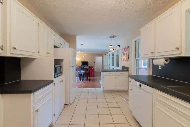 a kitchen with granite countertop a sink and white cabinets