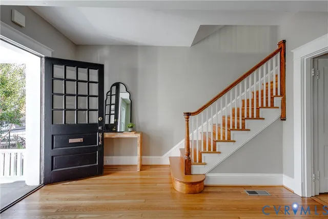 a kitchen with stainless steel appliances granite countertop a stove top oven a sink dishwasher a refrigerator and a dining table with wooden floor