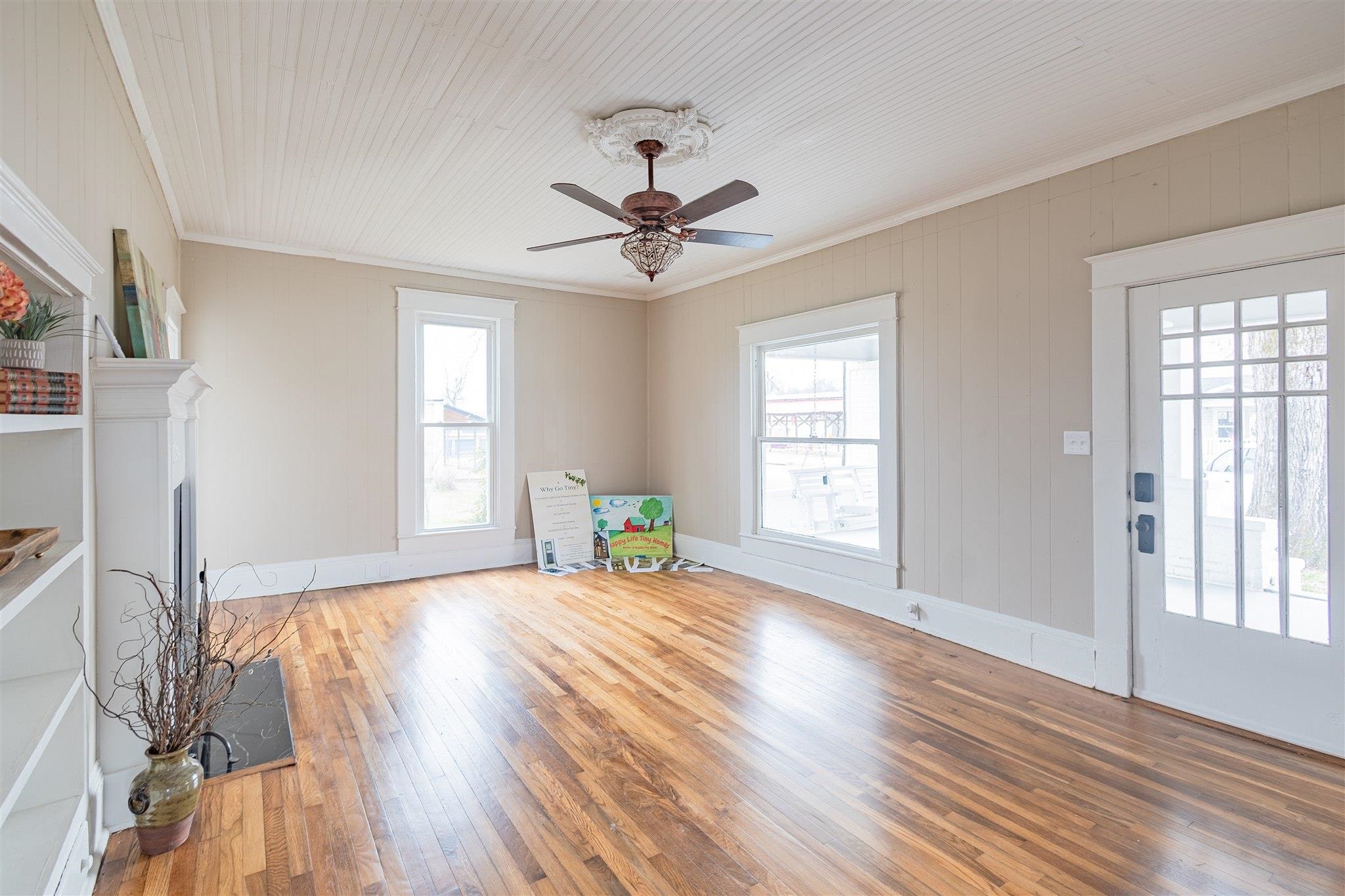 129 Warren Avenue Selmer, TN 38375 - Photo 15 of 28 an empty room with wooden floor chandelier fan and windows