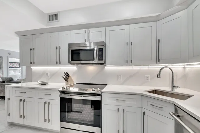a kitchen with white cabinets stainless steel appliances and sink
