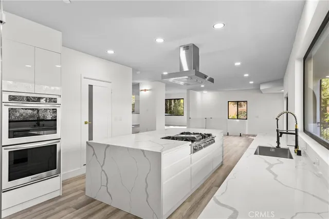 a large kitchen with stainless steel appliances a sink and a large window