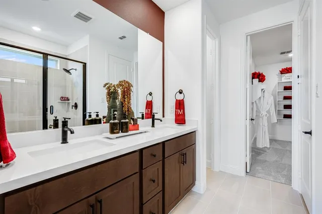 a en suite bathroom with a double vanity sink a large mirror and a shower
