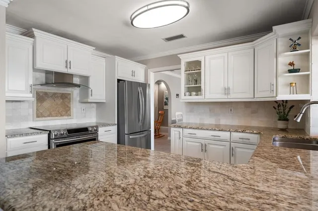 a kitchen with stainless steel appliances granite countertop a refrigerator and a stove top oven