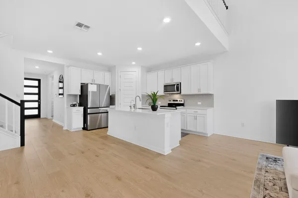 a kitchen with stainless steel appliances a refrigerator sink and white cabinets