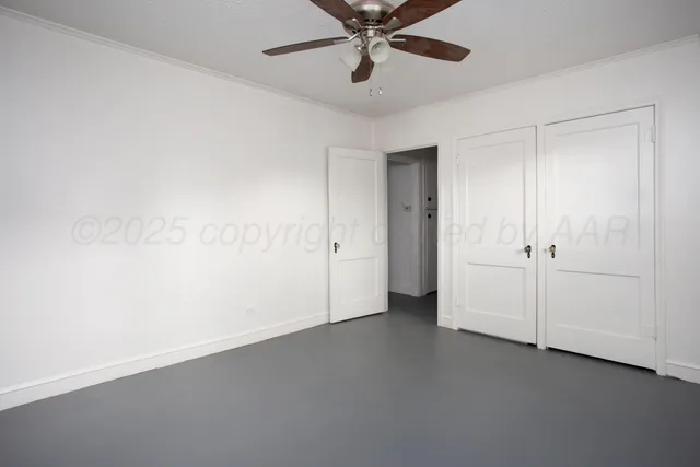 an empty room with a ceiling fan and closet area