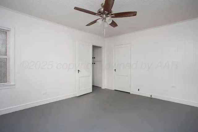an empty room with a ceiling fan and window