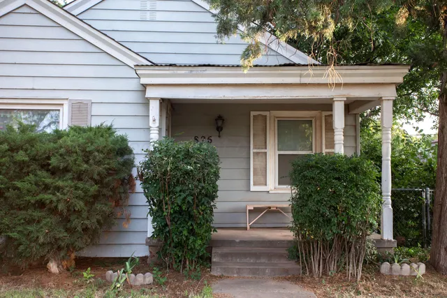 a view of a house with potted plants and a table and chairs
