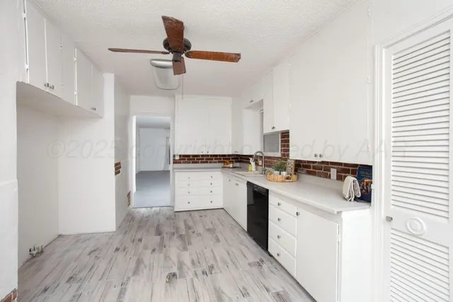 a kitchen with a sink dishwasher stove and white cabinets with wooden floor