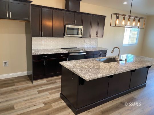 1045 Ocean Avenue Ridgecrest, CA 93555 - Photo 4 of 12 a kitchen with granite countertop cabinets appliances and wooden floor