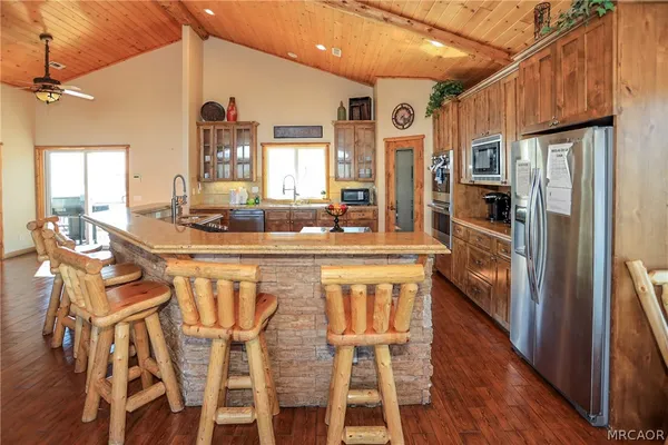 a kitchen with stainless steel appliances granite countertop a refrigerator a stove top oven and a sink