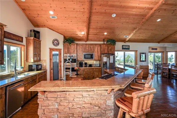 a kitchen with stainless steel appliances granite countertop a sink dishwasher and wooden cabinets with wooden floor