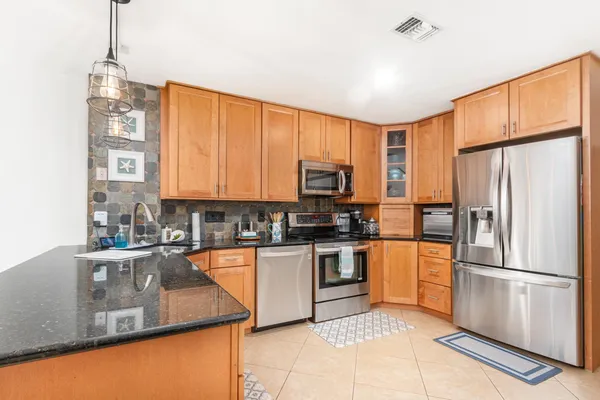 a kitchen with stainless steel appliances granite countertop a refrigerator and a stove top oven