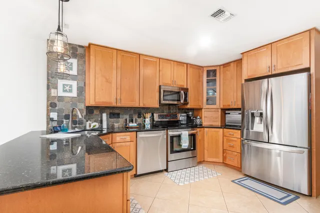 a kitchen with stainless steel appliances granite countertop a refrigerator and a stove top oven