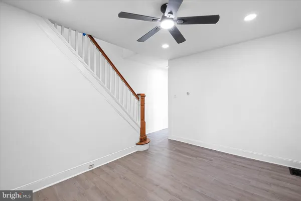 an empty room with wooden floor fan and windows