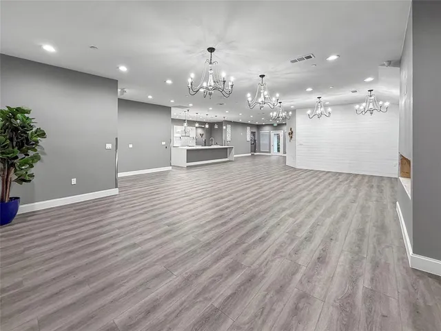a view of a big room with wooden floor and kitchen view