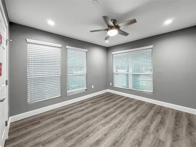 a view of an empty room with a window and wooden floor
