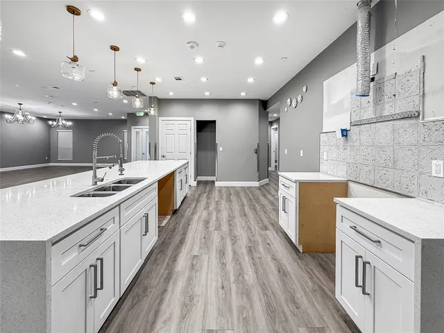 a large kitchen with stainless steel appliances a large center island wooden floor and a sink