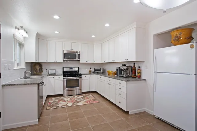 a kitchen with granite countertop a refrigerator and a stove top oven