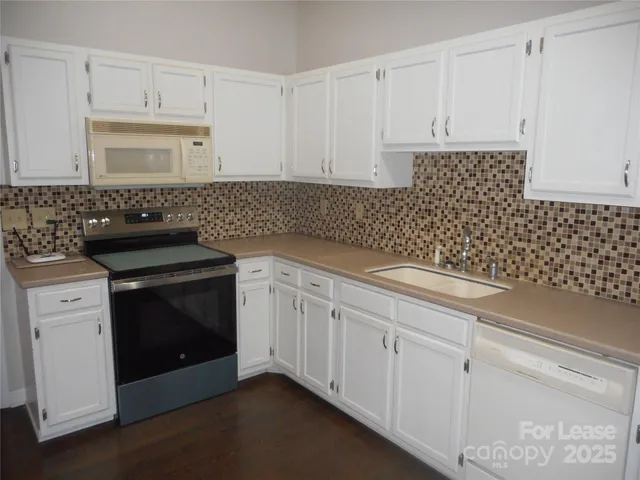 a kitchen with granite countertop white cabinets and black appliances