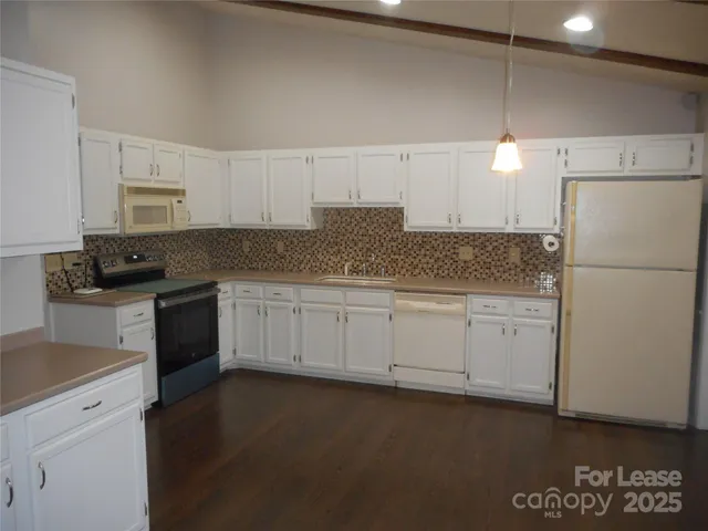 a kitchen with granite countertop white cabinets and refrigerator