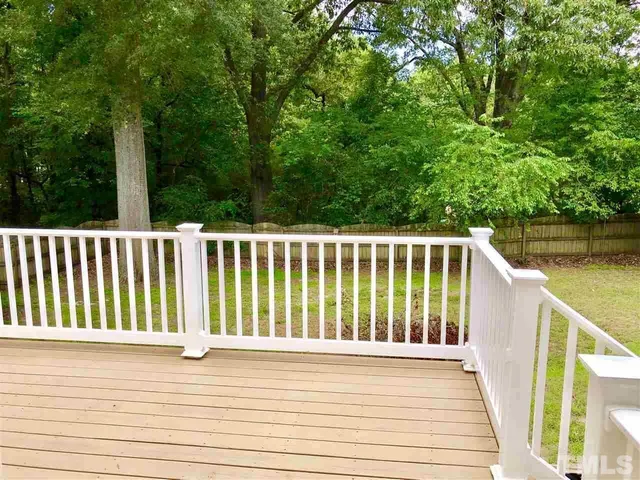 a view of a wooden deck and a yard with swimming pool