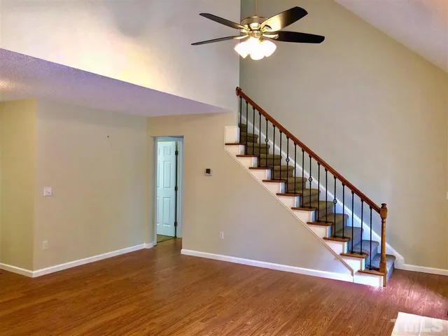a view of staircase with wooden floor and fan