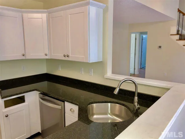 a kitchen with granite countertop white cabinets and sink