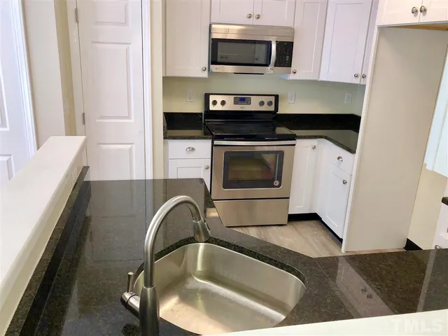 a kitchen with a sink and a stove top oven with wooden floor