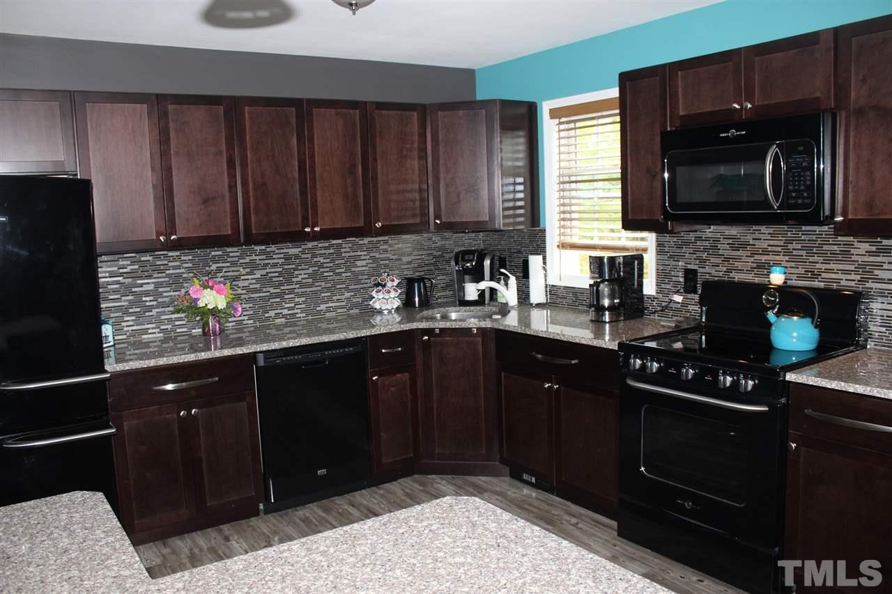 462 Pixley Pritchard Road Timberlake, NC 27583 - Photo 1 of 25 a kitchen with granite countertop wooden cabinets and black stainless steel appliances