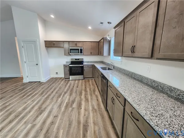 a kitchen with stainless steel appliances granite countertop a lot of counter space and wooden floors