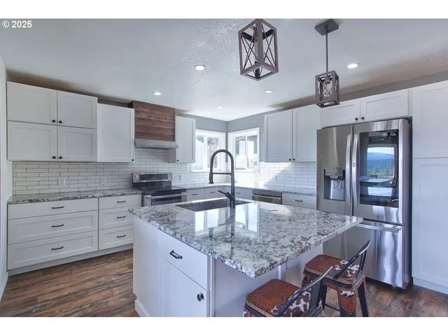 a kitchen with kitchen island granite countertop a sink cabinets and stainless steel appliances