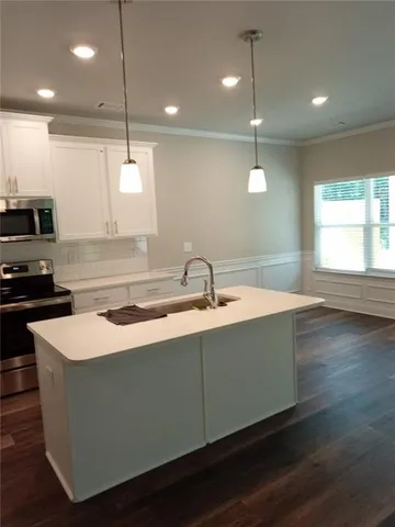 a kitchen with stainless steel appliances granite countertop a sink a stove and a wooden floor