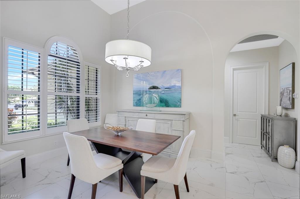 7323 Acorn Way Naples, FL 34119 - Photo 11 of 28 Dining room featuring arched walkways, a high ceiling, and light marble finish flooring