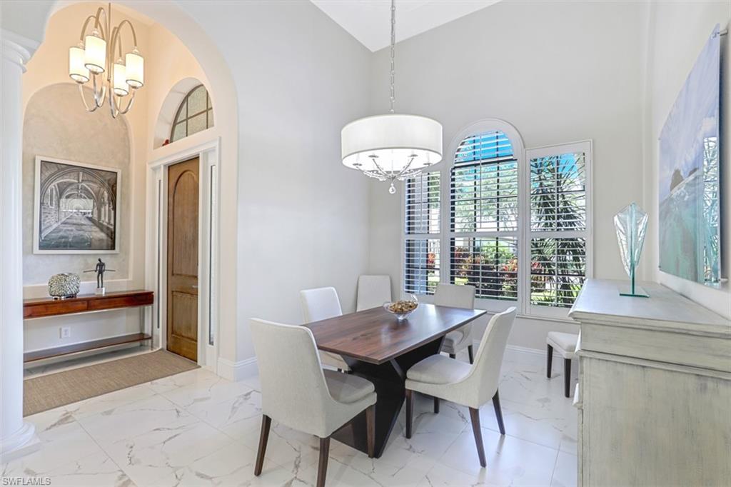 7323 Acorn Way Naples, FL 34119 - Photo 12 of 28 Dining space with hanging lights, light marble finish floors, arched walkways, and vaulted ceiling