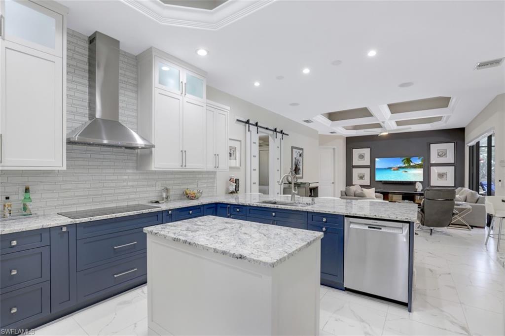 7323 Acorn Way Naples, FL 34119 - Photo 5 of 28 Two tone kitchen with a barn door, dual tone cabinetry, a peninsula, glass insert cabinets, and stainless steel dishwasher
