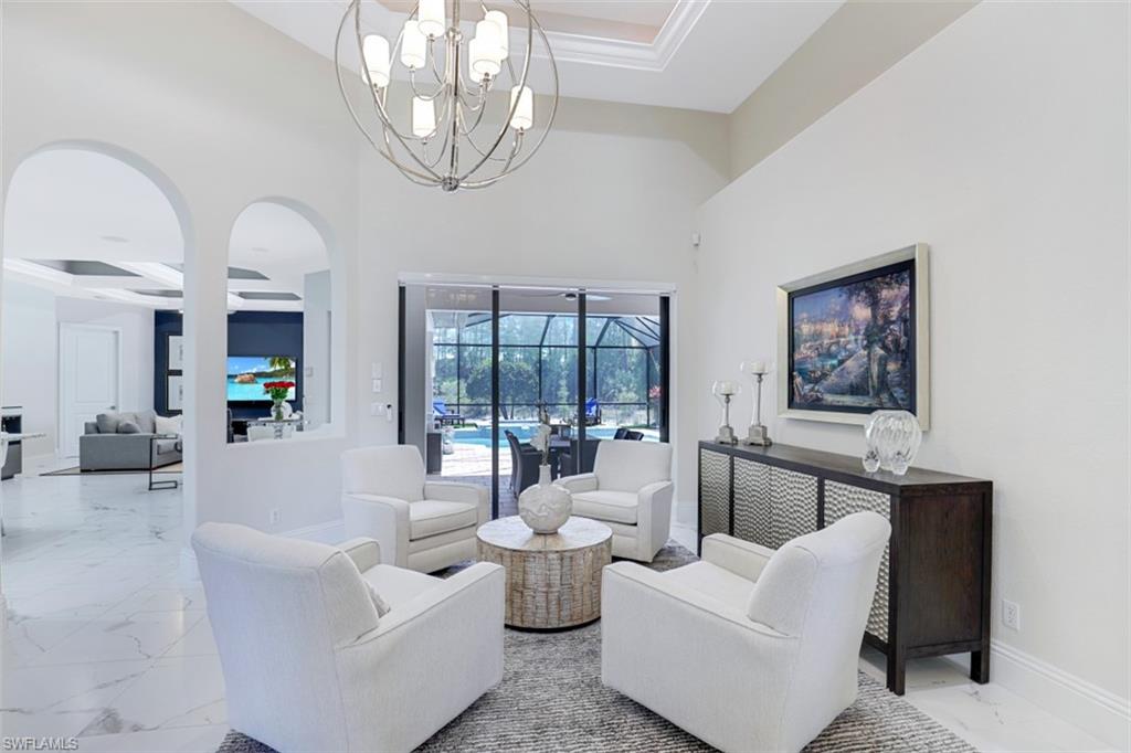 7323 Acorn Way Naples, FL 34119 - Photo 9 of 28 Living room with suspended lighting, light tile flooring, and a high coffered ceiling