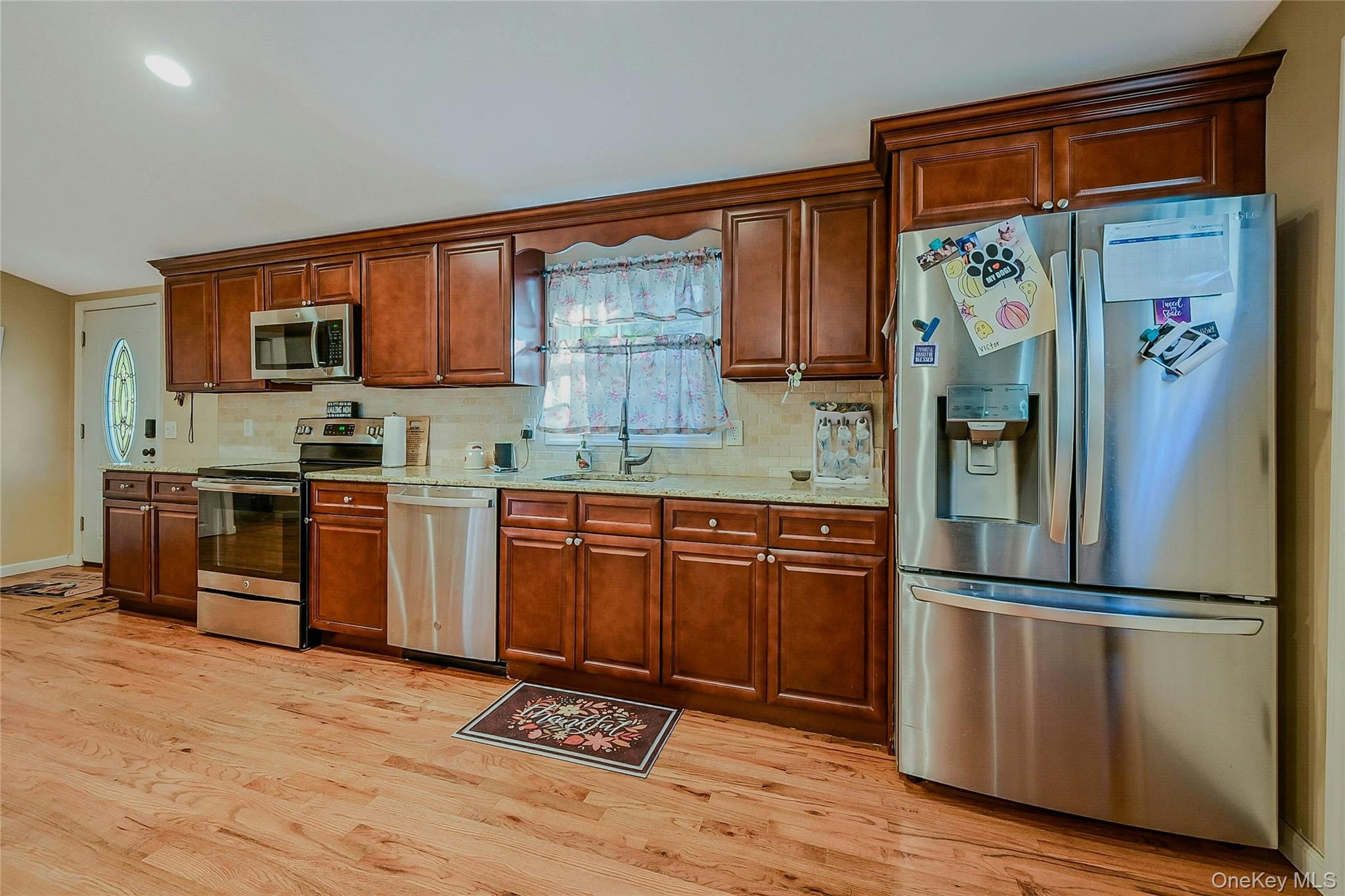 196 Church Drive Mastic Beach, NY 11951 - Photo 2 of 15 a kitchen with granite countertop stainless steel appliances a refrigerator cabinets and wooden floor