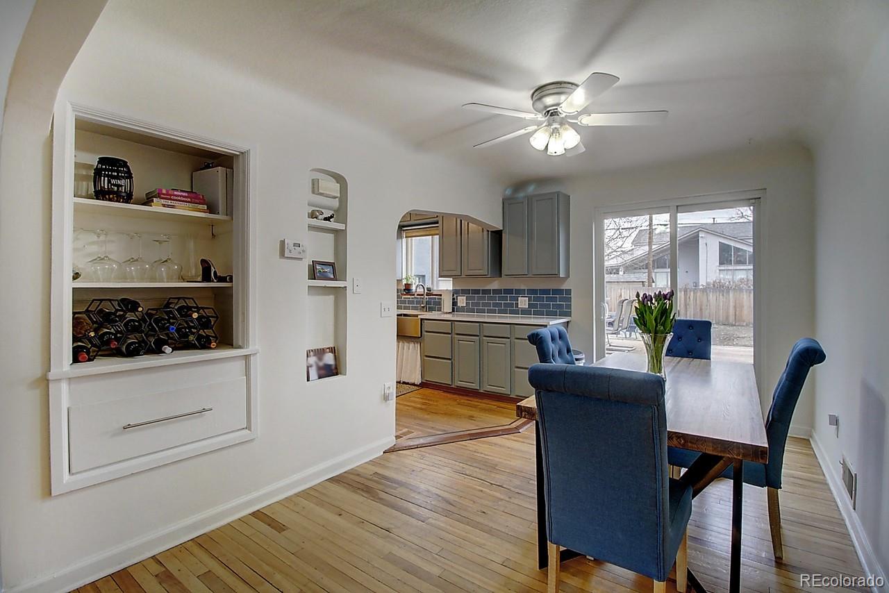 4075 Quay Street Wheat Ridge, CO 80033 - Photo 8 of 38 a kitchen with a refrigerator a stove top oven a dining table and chairs with wooden floor