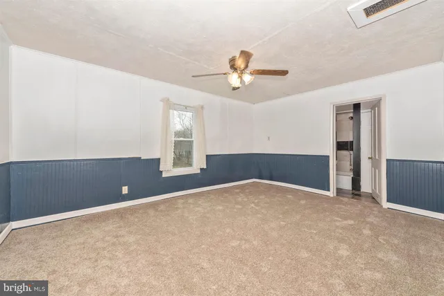 an empty room with windows and ceiling fan