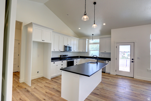 1257 North 1350th Street East Mapleton, UT 84664 - Photo 6 of 34 Vaulted ceiling kitchen featuring white cabinetry, black countertops, stainless steel appliances, and wood-finish flooring