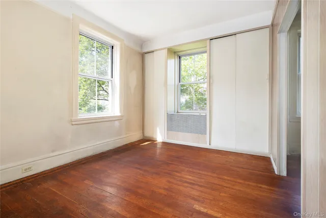an empty room with wooden floor and a window