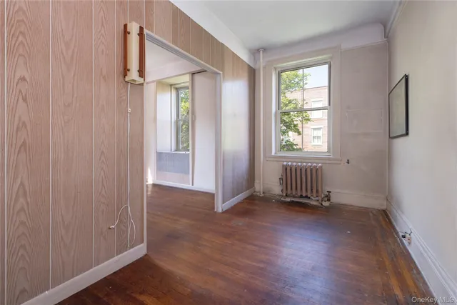 an empty room with wooden floor chandelier and windows